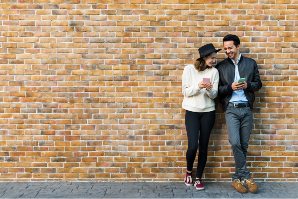 Girl and boy laughing by seeing each other phones