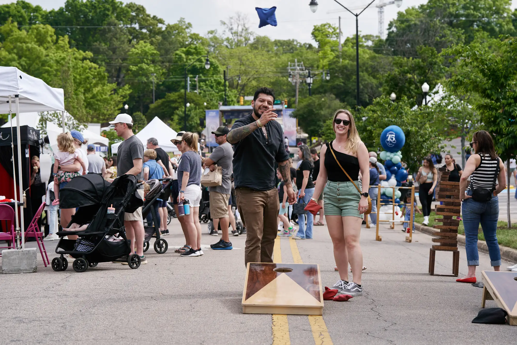 couple playing cornhole at Village District 75th Anniversary Celebration