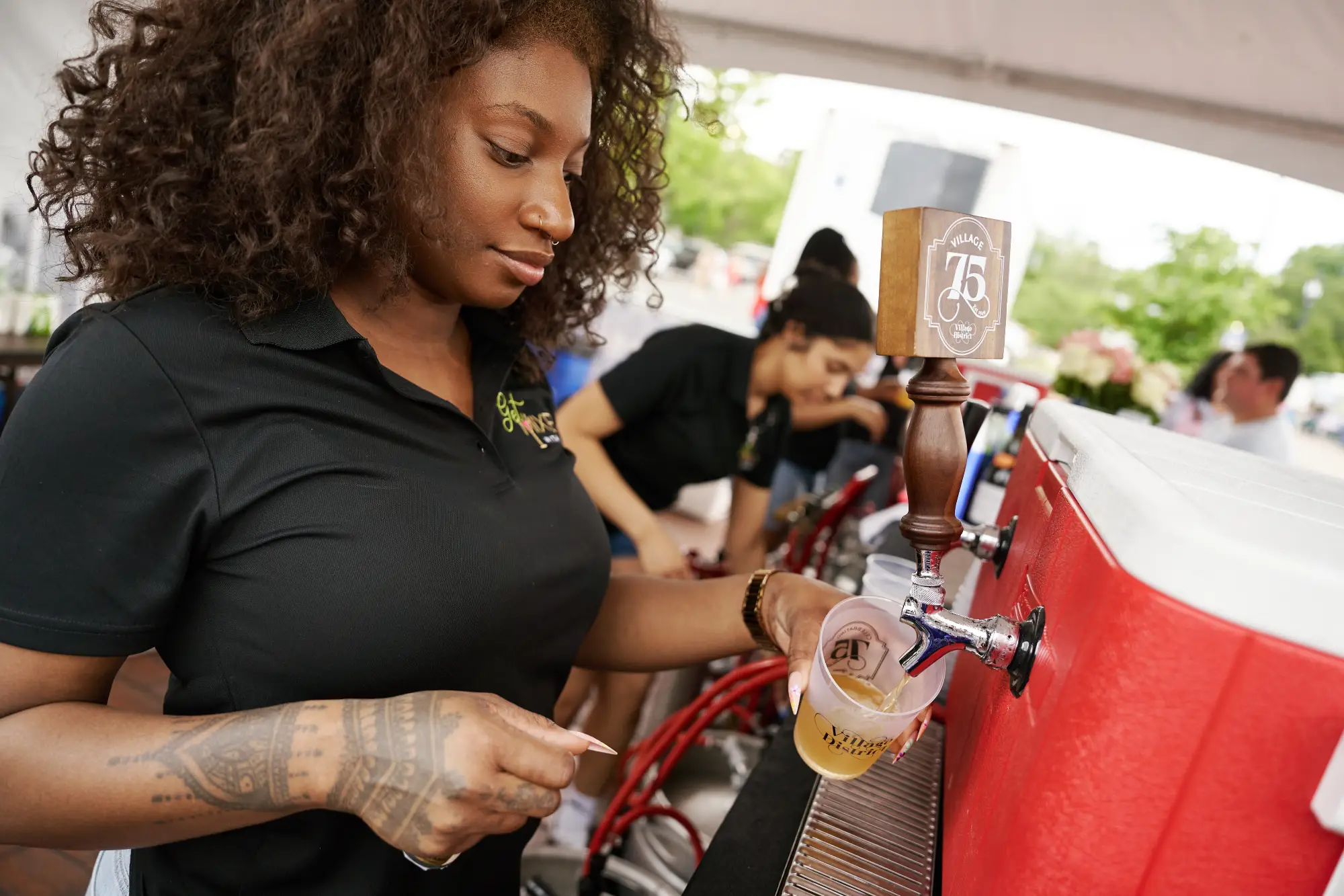 Girl pouring a beer at Village District 75th Anniversary Celebration