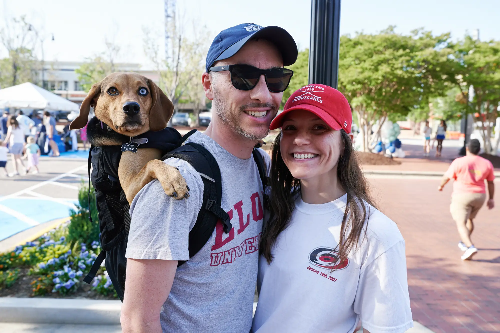 a couple smiling with dog in backpack