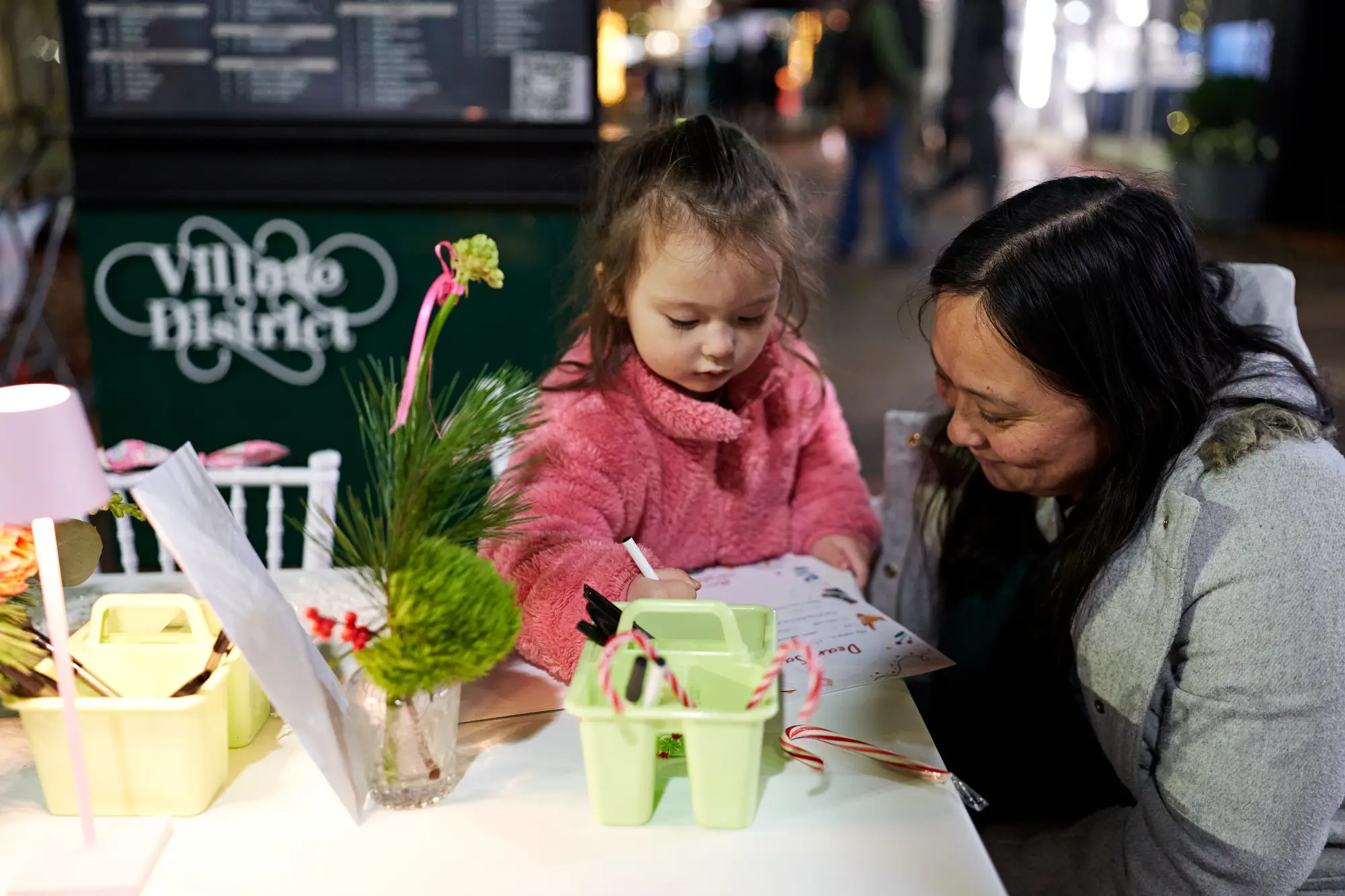 a mom helping a little girl write a letter to Santa